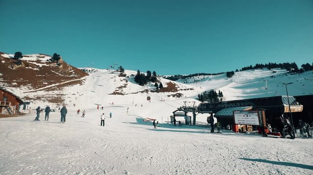 Unrecognizable skiers at Chamrousse ski resort with a digital screen displaying a weather or safety warning, winter sports scene in the French Alps