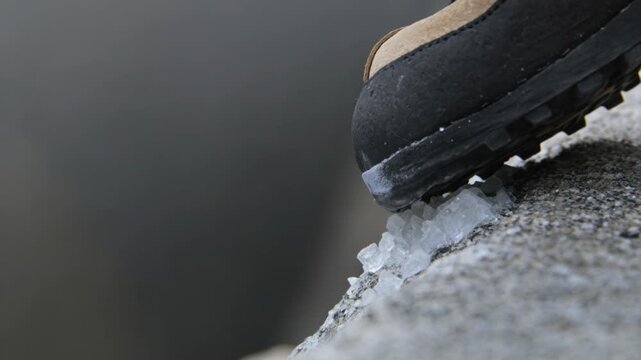 Climbing shoe edging on a microscopic granite crystal seam above a blurred abyss dramatically