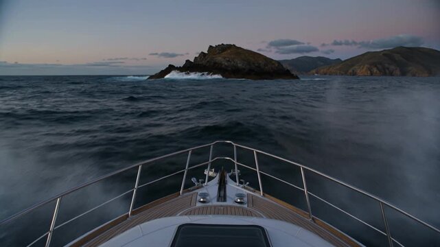 Yacht bow camera cuts through midnight blue swell toward a distant glowing horizon line