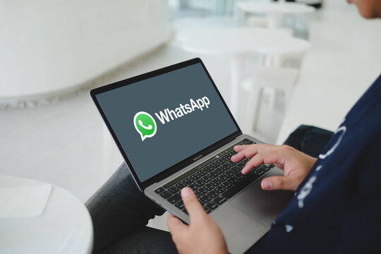 Bangkok, Thailand. April 15, 2026; A man sitting in a modern office space holds a laptop displaying the WhatsApp messenger logo on the screen.