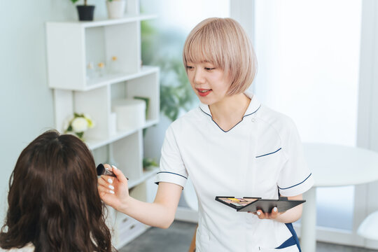 メイクするハイトーンヘアの女性スタッフ