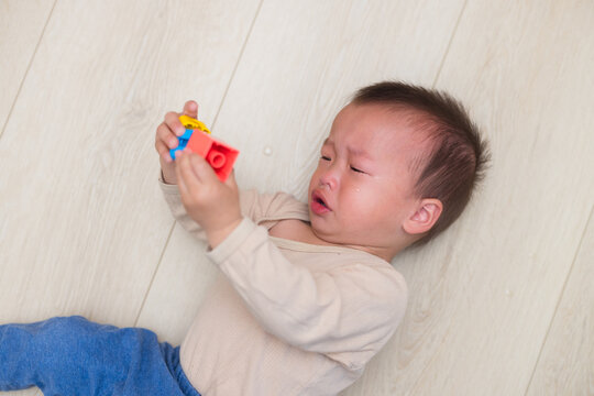 Crying little boy lying on wooden floor