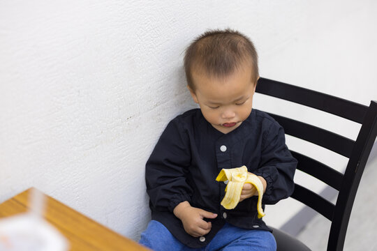Little boy enjoying banana snack in restaurant
