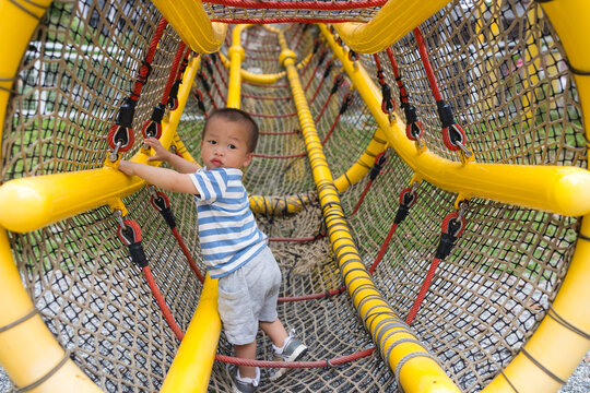 Little boy climbing rope net at outdoor playground park