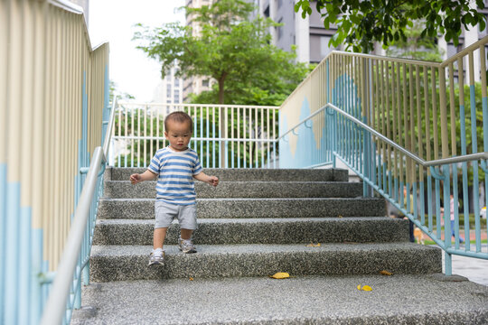 Little boy walking up stone stairs at outdoor playground park