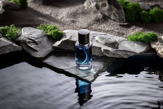 Modern blue perfume on black stones illuminated by moonlight.