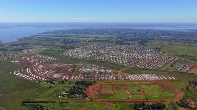 Drone pan from right to left over vast Itaemb&eacute; Guaz&uacute; neighborhood, revealing Posadas skyline and Paran&aacute; River bend toward Paraguay.