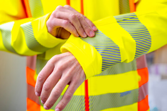 Close-up person wearing bright yellow reflective safety jacket, hands adjusting sleeve reflective tape uniform, Ready for work, clear and confident, worker gear, Safety first, confidence and teamwork