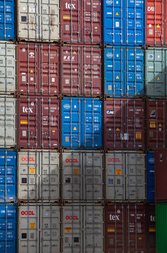 Stacked Tex and OOCL shipping containers forming a colorful grid at an industrial port