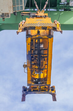 Yellow container spreader suspended from gantry crane near the Port of Oakland