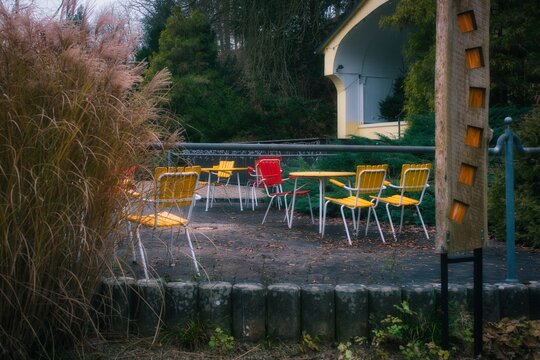 A red chair among the scattered yellow chairs in the park