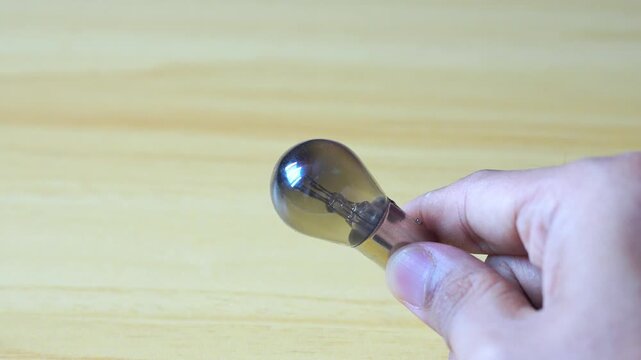 Hand holding light bulb on wood background