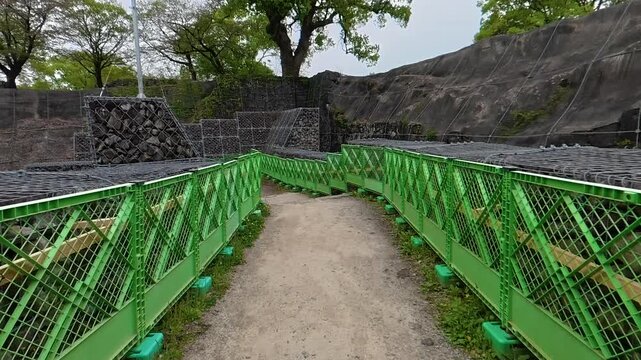 POV walking through a narrow path enclosed by construction fences and safety barriers