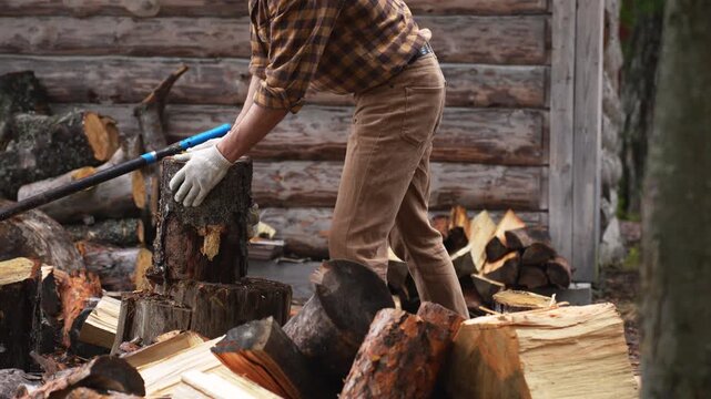 Close up of chopping wood with an axe against a log wall background. Slow motion 4K ProRes 422 manual labor.
