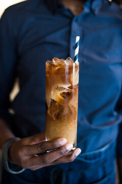 Person in Blue Shirt Holding Iced Coffee with Milk
