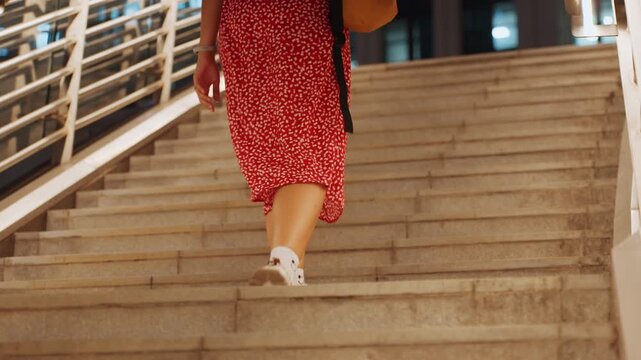 Black woman climbing concrete stairs in red dress and white sneakers, closeup leg movement, sock detail and sole tread, brisk urban ascent, commuter energy and athletic stride, nighttime city steps,