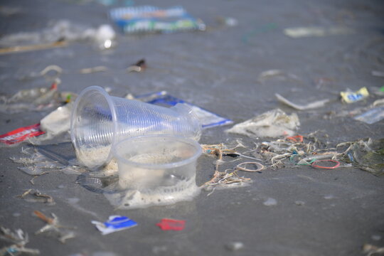 Environmental Crisis: Plastic Waste and Microplastics Polluting a Pristine Sandy Beach at Sunset