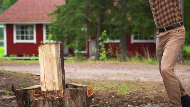 Strong man splitting a tough wooden log with an axe. Slow motion 4K ProRes 422 footage of successful manual labor
