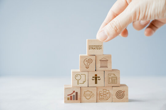 government strategy administration policy governance leadership planning concept with businessman hand building a wooden block pyramid on office background for public sector development.
