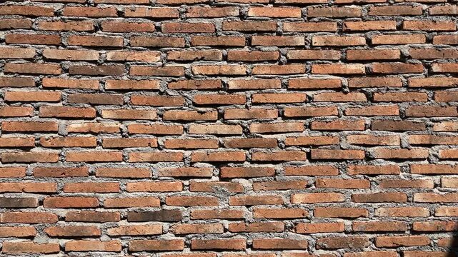 Weathered brick wall shows aged, rustic charm. Mortar lines reveal time's gentle wear. Red bricks stand strong, textured and worn. Ideal for vintage, industrial, or architectural themes. side view. 