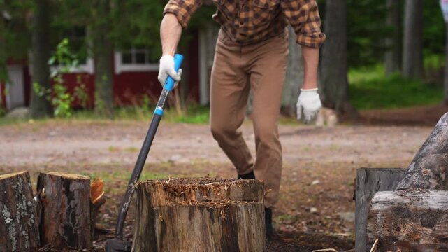 Strong man splitting a tough wooden log with an axe. Slow motion 4K ProRes 422 footage of successful manual labor.
