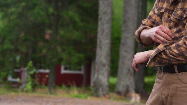 Close up of a man rolling up his sleeves before work. Slow motion 4K ProRes 422 footage of a lumberjack in a plaid shirt.