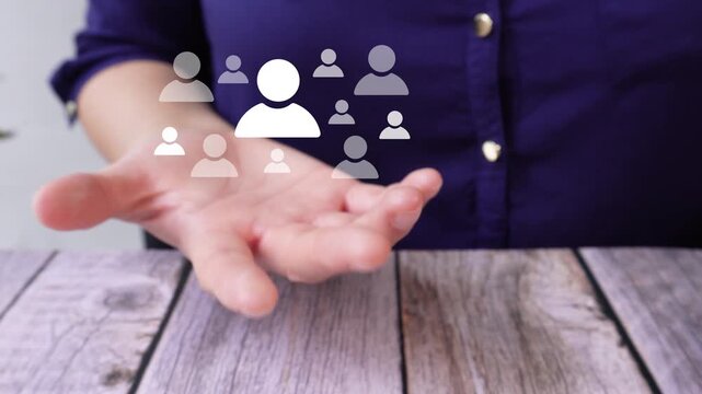 Close-up of a woman's hand on a table holding an animation that highlights different avatars of people, a concept for personnel selection.