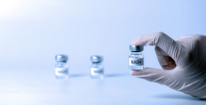 Gloved hand holds nad+ vial showing hopeful longevity treatment concept representing modern medical science health care and antiaging therapy