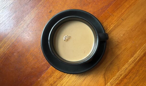 top view of hot coffee on the black cup. isolated on wooden table. brown, chocolate. bright, natural light, sunlight, sunshine. high angle, above, flat lay. cafe, coffee shop, restaurant. menu. drink.