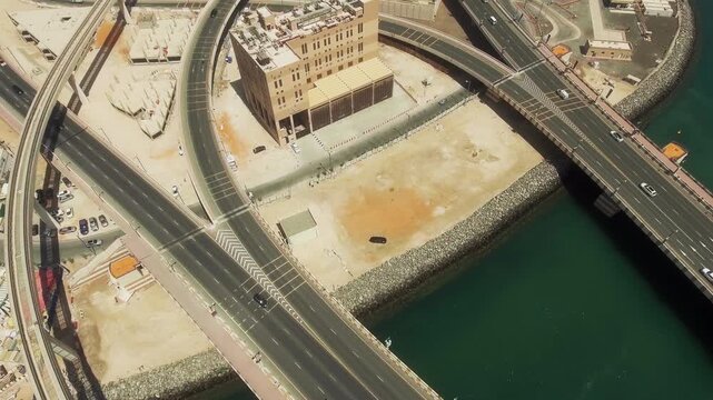 Top down drone view of curved roads over water and sand with urban infrastructure and buildings in Dubai United Arab Emirates