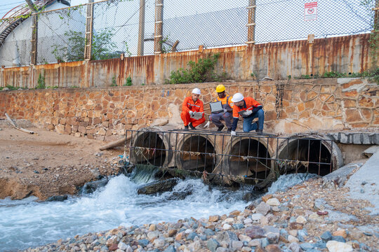Engineers inspect water drainage system urban area safety assessment industrial site ground level environmental awareness