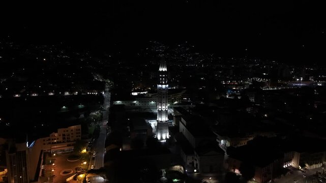 Aerial night photograph of an illuminated bell tower in Malgrate with sparkling Lake Como town lights.