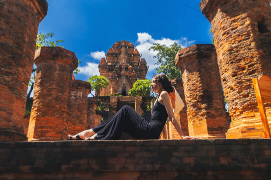 A female tourist sit on the background View of Po Nagar Cham towers complex
