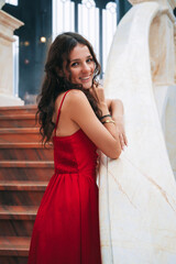 Fototapeta premium A romantic princess stands gracefully in a red dress inside an ancient castle.