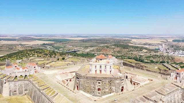 Aerial view of Forte de Nossa Senhora da Graca, a historic hilltop fortress surrounded by scenic countryside in Elvas, Portugal. Bright summer sky enhances the dramatic landscape and architectural