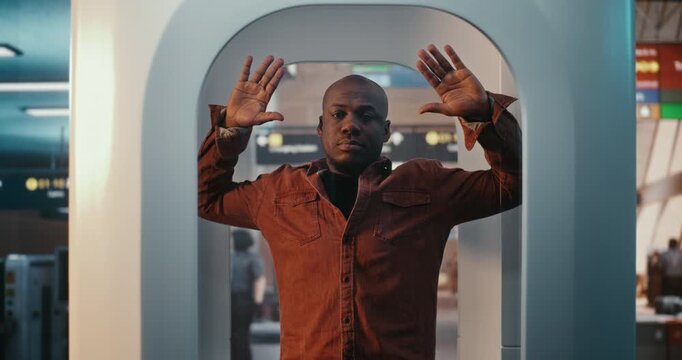 Focused Male Traveler Undergoes Full Body Electronic Search at Busy Terminal Checkpoint. Standing Still With Arms Raised, Man Compliance With Strict Airport Security Regulations. Travel Guidelines.
