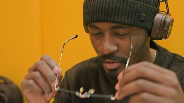 Operator examines sound system carefully. Person finetunes audio devices inside sealed booth. Male operator thoroughly inspects and calibrates audio equipment inside soundproof chamber