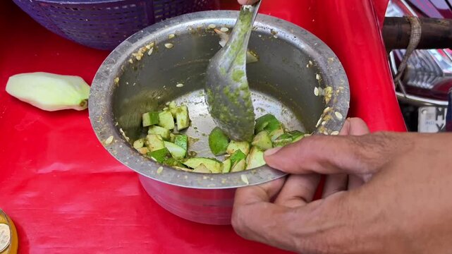 Indian street food vendor mixing raw mango slices with spicy masala and chutney