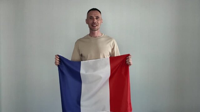 A happy man holds a French flag. An enthusiastic fan cheers for his national team