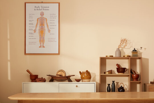 Wooden shelves, herbal jars, and acupuncture meridian chart displayed in traditional oriental medicine apothecary interior.