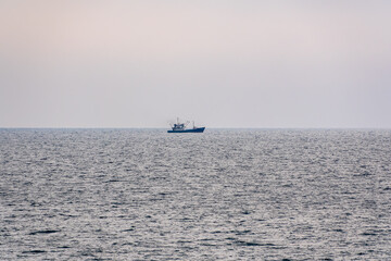 Obraz premium Fishing boat in blue sea and clear sky with birds flying overhead.