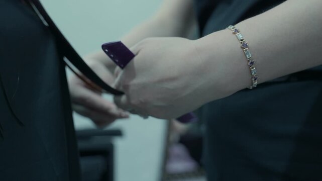 A hairdresser cuts the ends of his client's hair in a beauty salon.