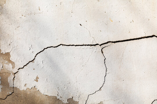 weathered white concrete wall with deep horizontal crack and texture