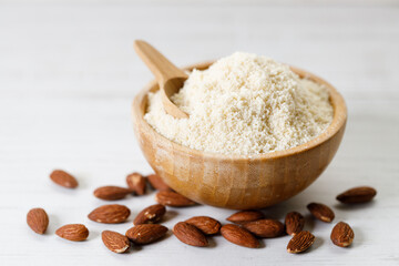 Almond meal, Almond flour, in wooden bowl with almond nuts on white table. © shersor