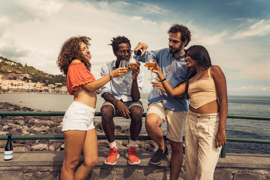 Multicultural group of friends drinking craft beer together by the sea