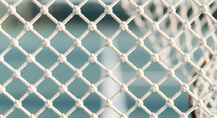 Fototapeta premium Detailed close-up of a white knotted rope net with diamond pattern, sharp focus and soft blurred background, ideal for texture or backdrop use.