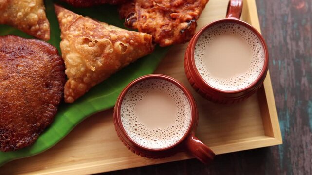 Assorted Kerala snacks Ulli vada spicy onion fritters  Parippu Vada or Paruppu Vadai made with toor dal Samosa crunchy triangular shaped wraps Neyyappam bonda and milk tea undampori. 