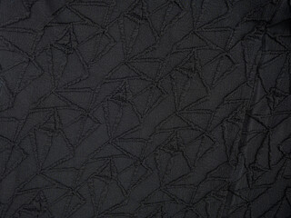 Fototapeta premium Dark charcoal fabric texture with geometric stitched quilt pattern, wrinkled textile surface, abstract background with subtle shadows and seams.