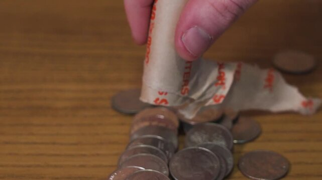 Unwrapping US quarters and letting them fall into the pile below.