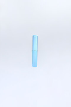 Minimalist lipstick cosmetic container blue cylindrical tube stands alone. Elegant cylindrical beauty product elegance beauty packaging with soft blue gradient finish and smooth reflective surface  